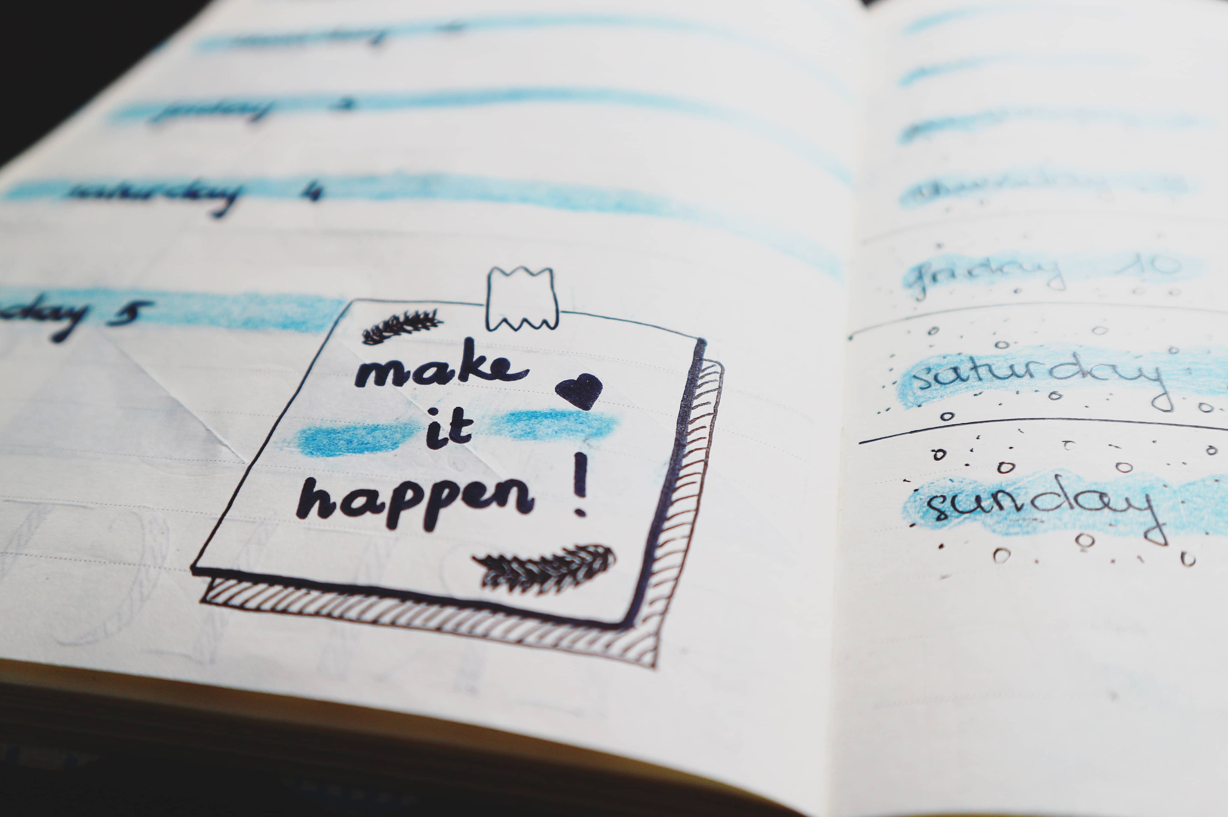 Open wedding planning planner with motivational quote "make it happen!" and hand-drawn calendar for Friday to Sunday.