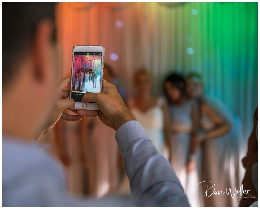 A person capturing a group photo with a smartphone at a colorful event.
