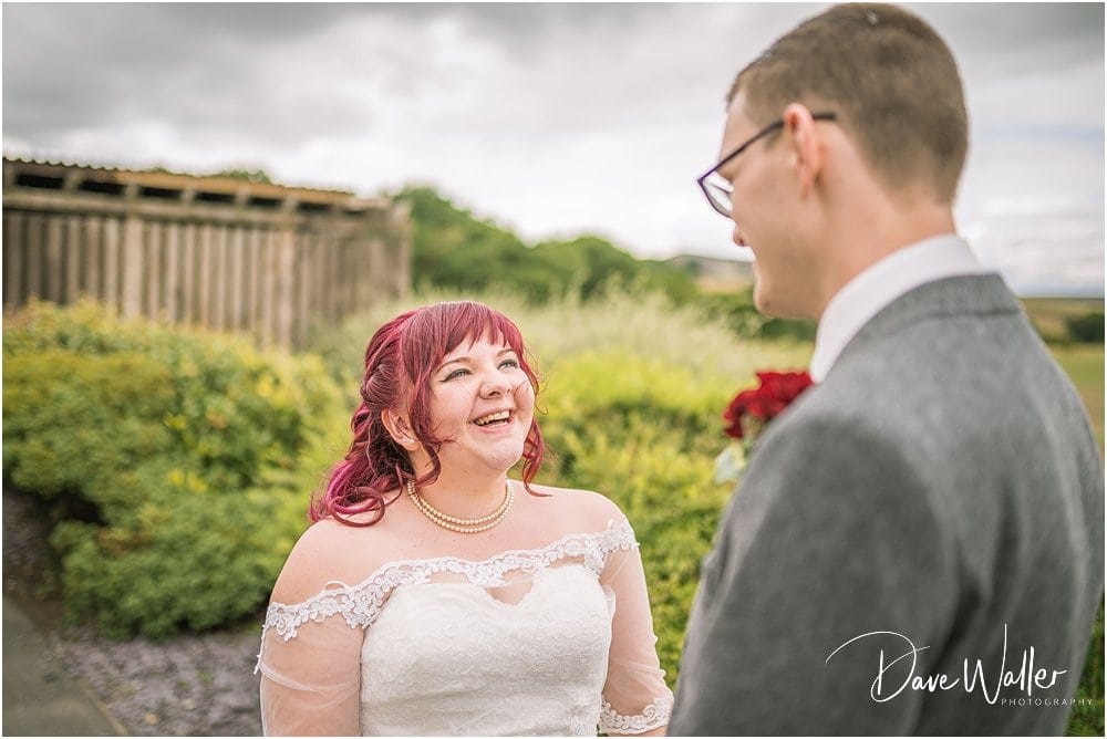 Bride with pink hair smiling at groom in outdoor setting at the Huntsman Inn, Holmfirth, West Yorkshire.