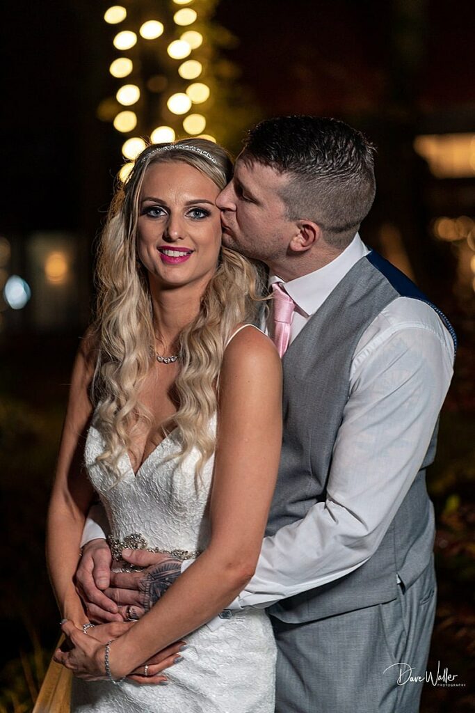 Couple in wedding attire with romantic evening lights.