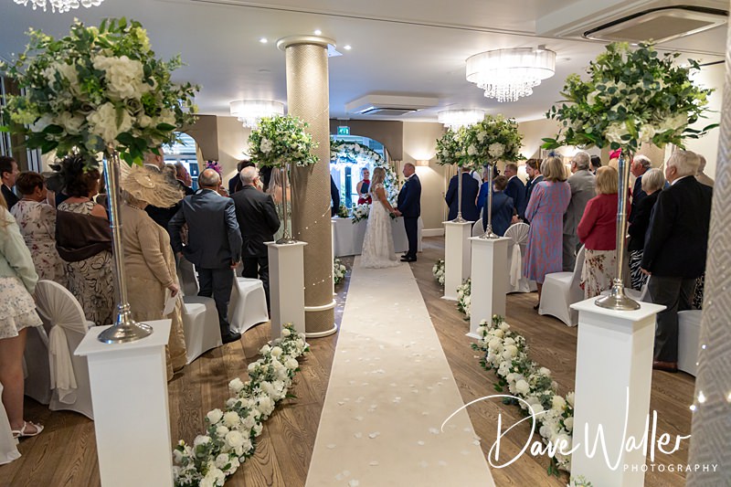 Wedding ceremony aisle with guests and floral decorations.
