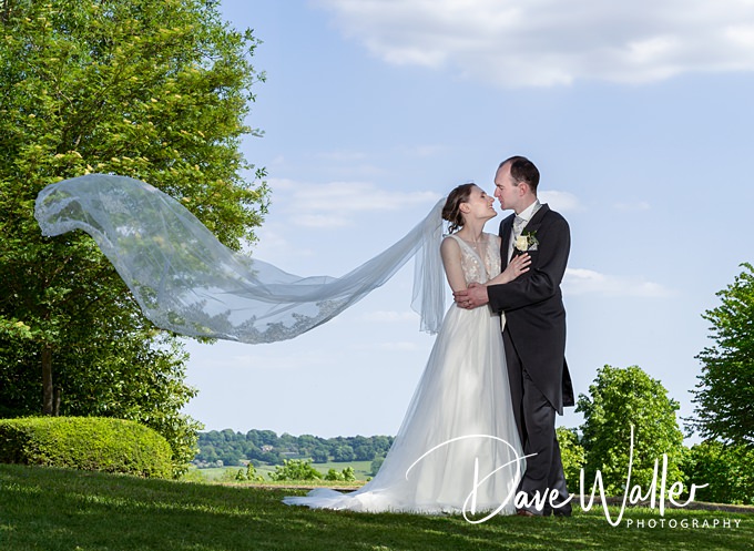 Couple kissing at wedding with long veil flowing.