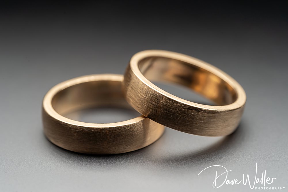 Gold wedding bands on gray background.