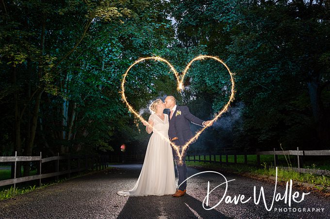 Couple kissing with sparkler heart at night.