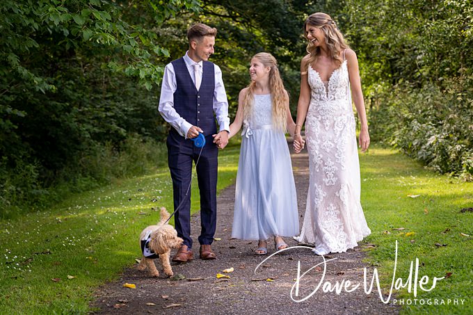 Family and dog walking outdoors in formal attire.