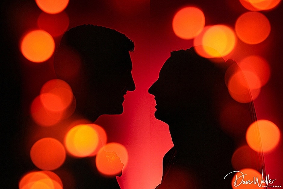 Silhouettes of two individuals facing each other against a backdrop of warm bokeh lights capture the essence of Wentbridge House Hotel Wedding Photography.