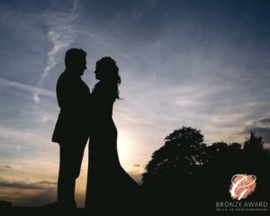 A romantic silhouette of a couple embracing against a twilight sky, capturing a moment of love and togetherness, with the proud display of a photography bronze award stamp.