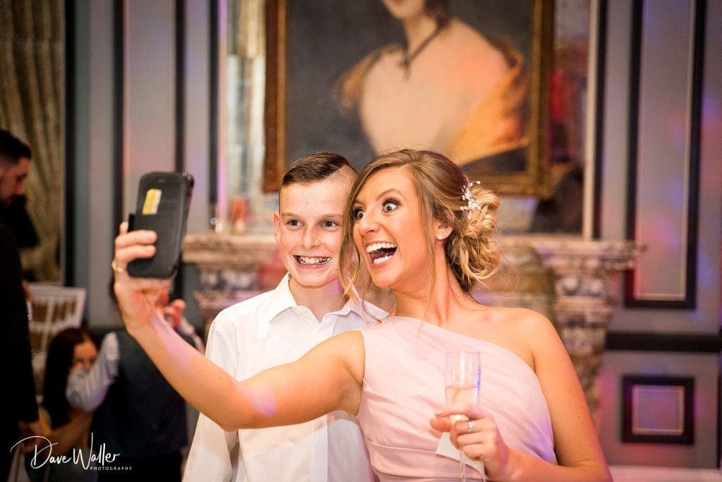 A joyful moment captured in a selfie, as a young boy and a woman in a celebration dress beam with happiness at a festive event.