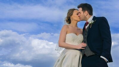 A romantic moment under a vast sky: newlyweds share a tender kiss, encapsulating their love and the beginning of their lifelong journey together.