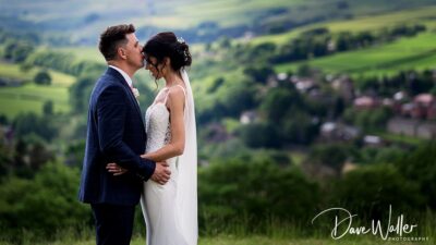 Holly & Mathew, in wedding attire, sharing a tender moment with a picturesque Vineyard landscape in the background at Holmfirth Vineyard.