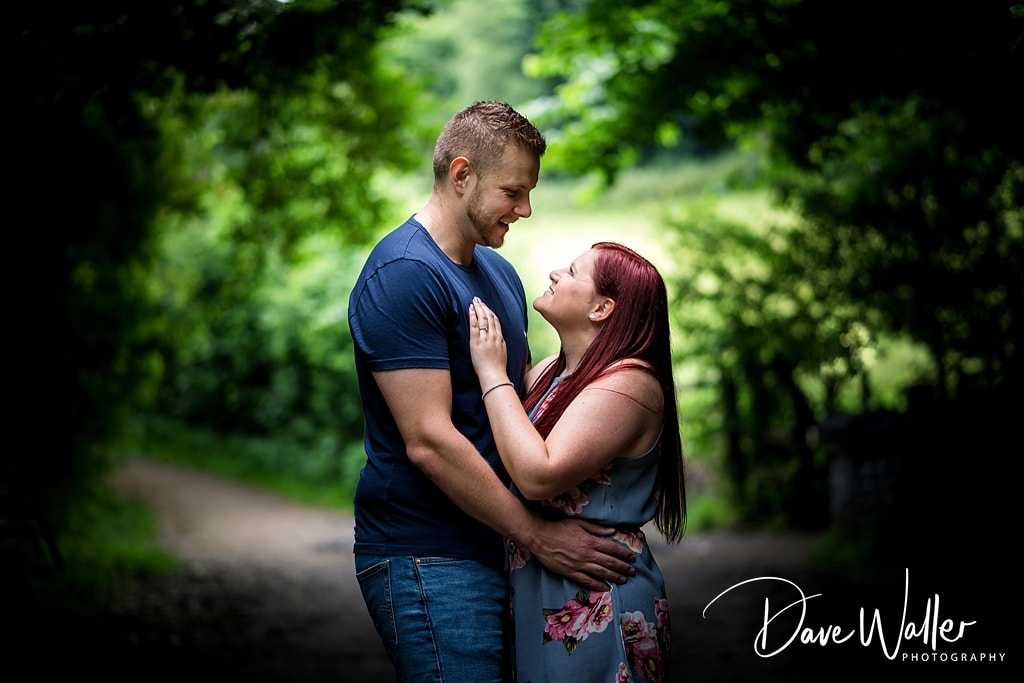 A tender moment during a couple shoot as they gaze into each other's eyes amidst a tranquil forest backdrop, conveying a sense of love and connection.