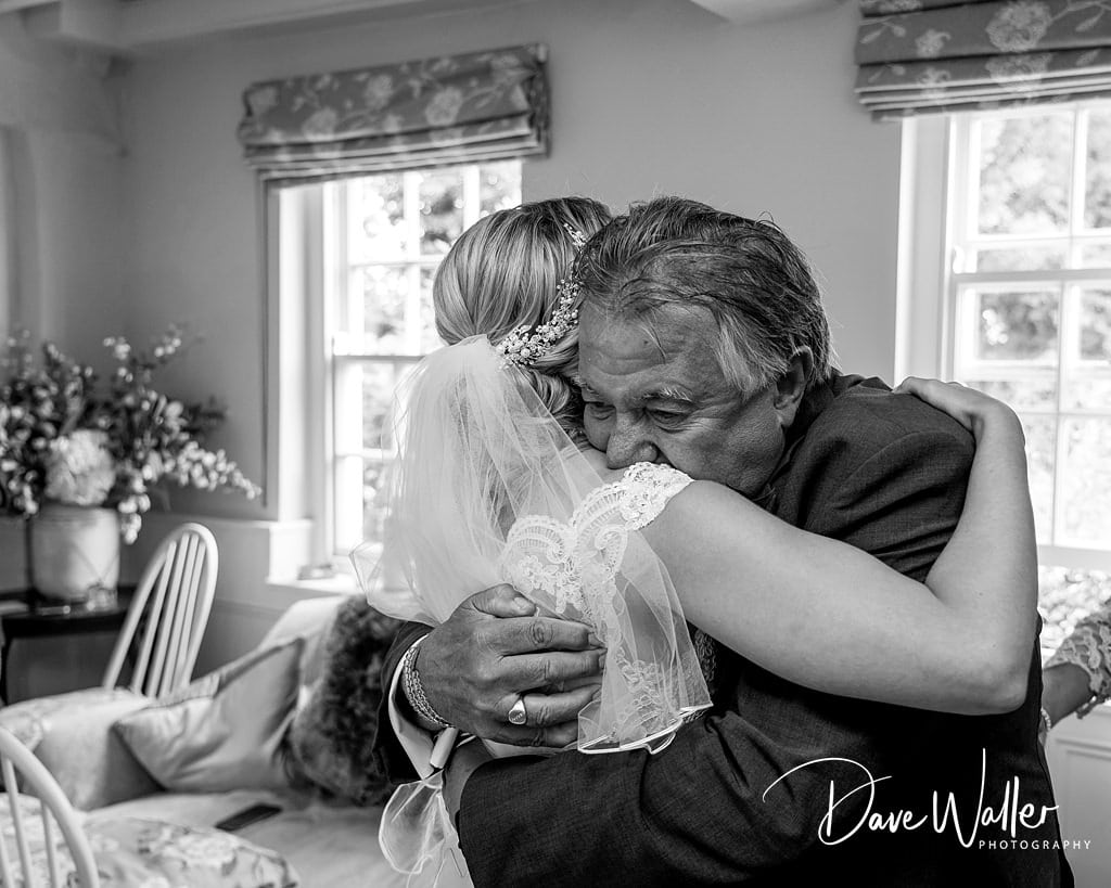 Tender embrace: a heartfelt moment as Normans Wedding Photography captures the father hugging the bride, conveying a mixture of joy and sentiment on Rebecca & Jonathan's special day.