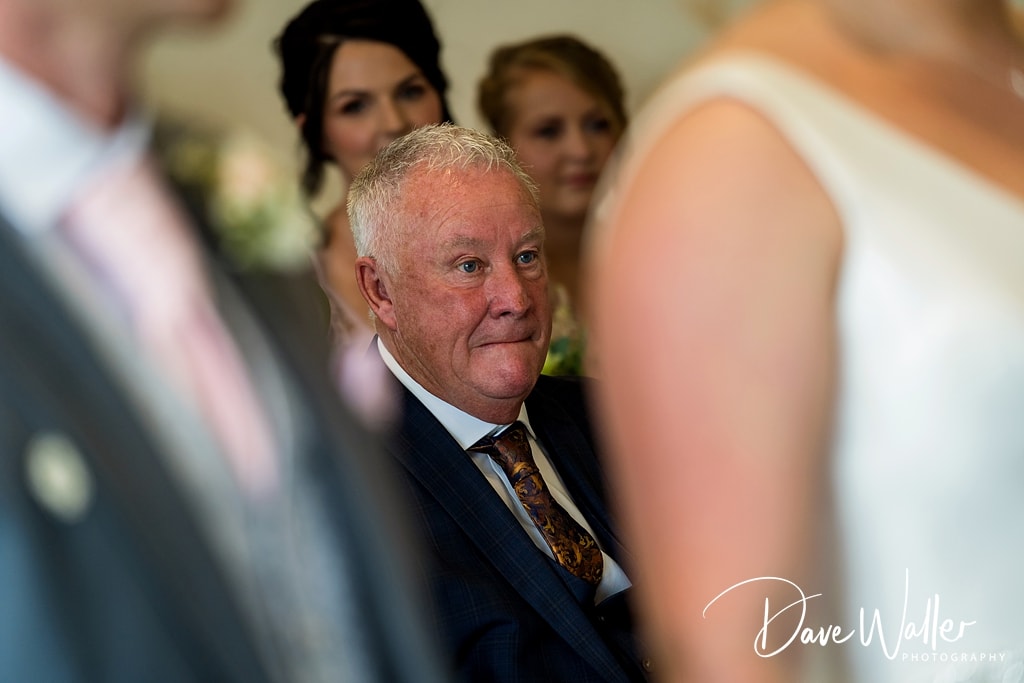 A proud and emotional father gazes affectionately at his daughter during Sophie & Nicholas's wedding ceremony at Hollins Hall Hotel.