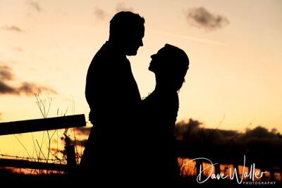 Silhouetted embrace at their Wentbridge House Wedding: Emily and Duncan share a tender moment against the backdrop of a sunset sky.