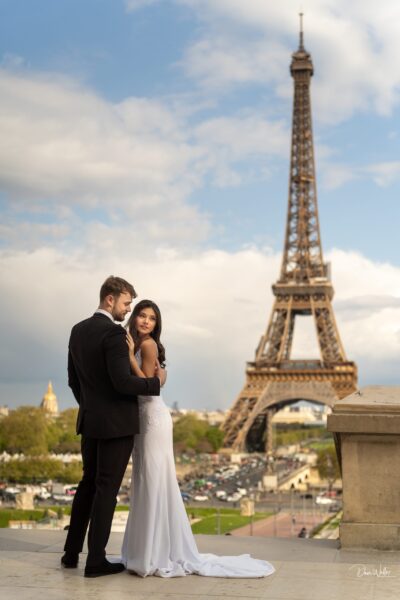A couple embracing tenderly with the eiffel tower as a romantic backdrop.