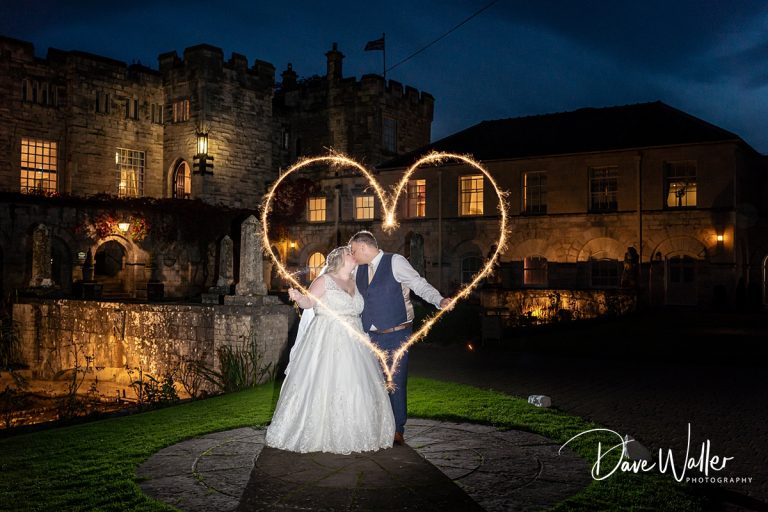 Couple kissing at night in front of Hazlewood Castle, with a heart-shaped light trail surrounding them.