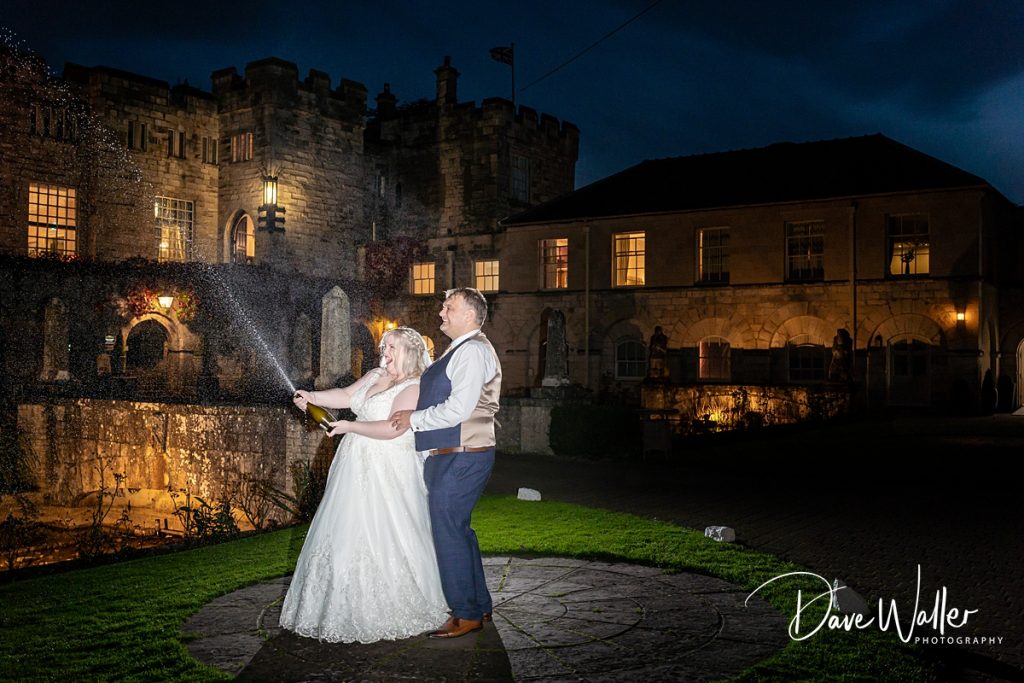 A magical evening: Kirsty & David in wedding attire light up the night with a sparkling celebration in front of the grand Hazlewood Castle.
