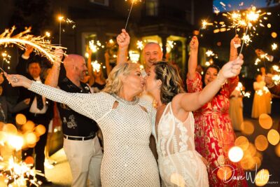 Couple kissing at wedding with sparklers.