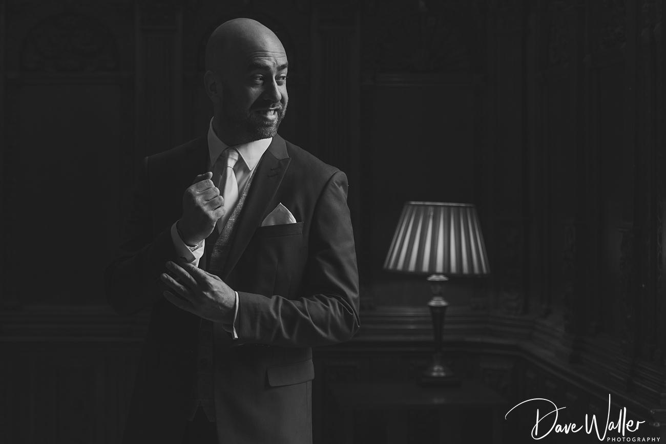 Man in suit adjusting cufflink, elegant, monochrome portrait.