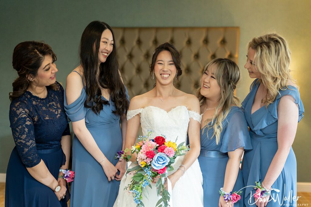 Bride and bridesmaids smiling with bouquets at wedding