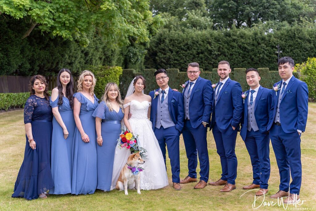 Wedding party with bride, groom, and dog outdoors.