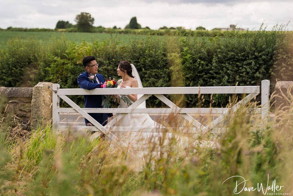 Wedding couple by countryside gate.