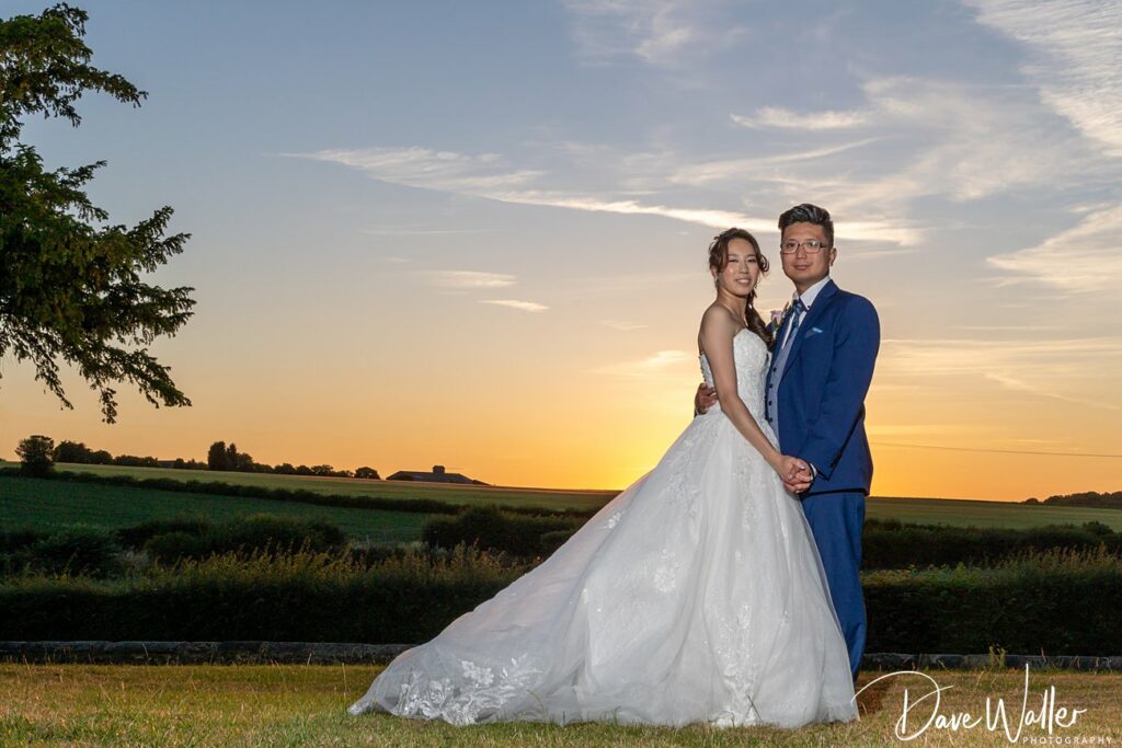 Couple at sunset wedding in countryside.