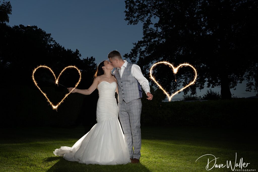 Bride and groom with sparkler hearts at night wedding.
