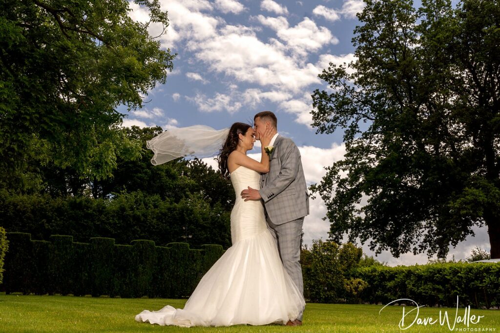 Bride and groom kissing outdoors with floating veil.