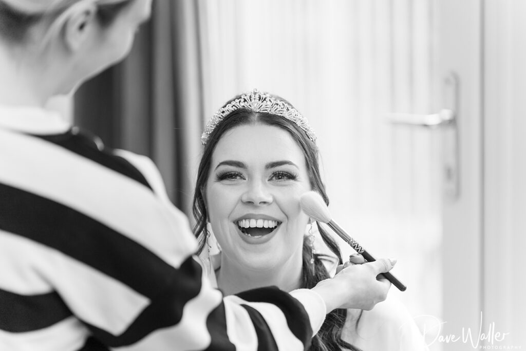 Bride laughing during makeup application.