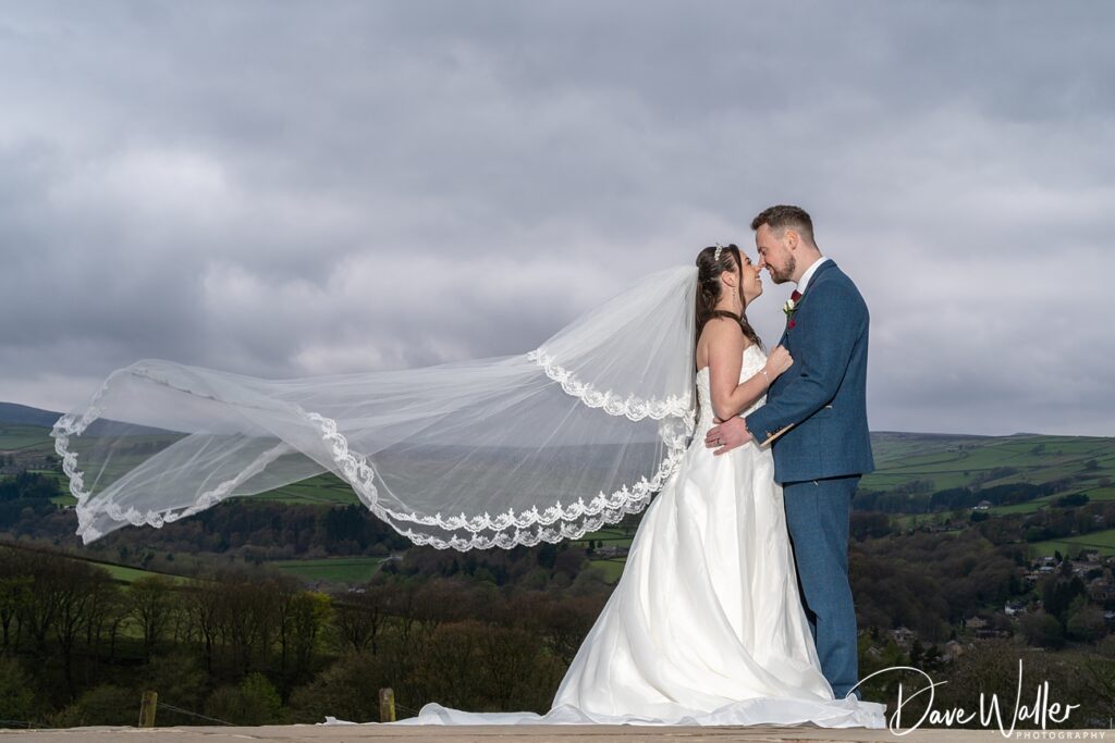 Bride and groom kissing outdoors with flowing veil.