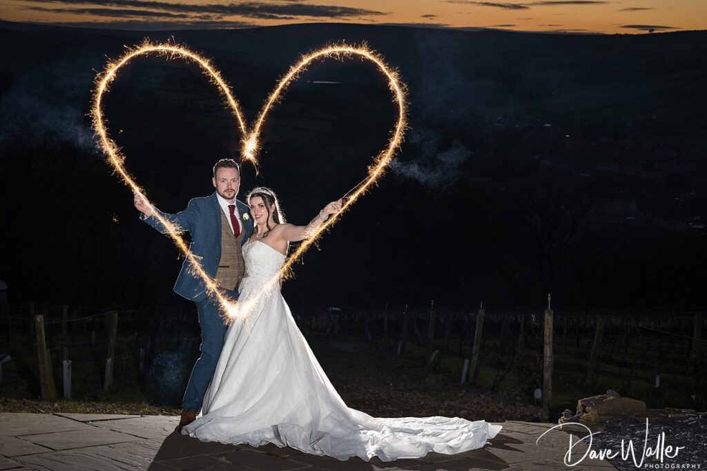 Couple with sparkler heart at twilight wedding.