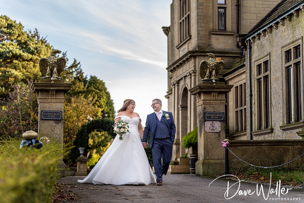 Bride and groom walking outside historic hotel building.