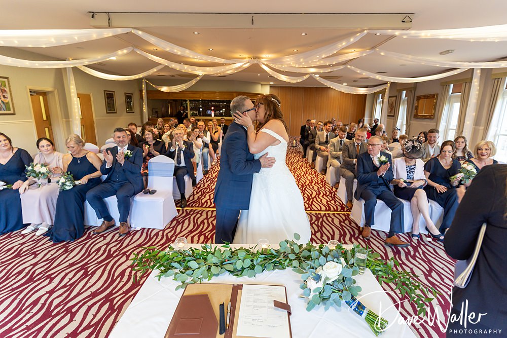 Bride and groom kissing at wedding ceremony.
