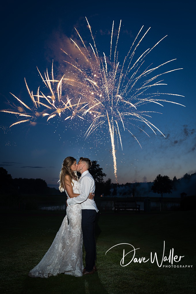 Couple kissing under evening fireworks display.