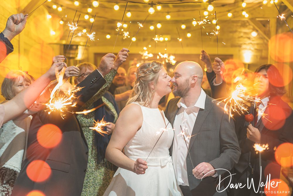 Couple kissing amidst sparklers at wedding celebration