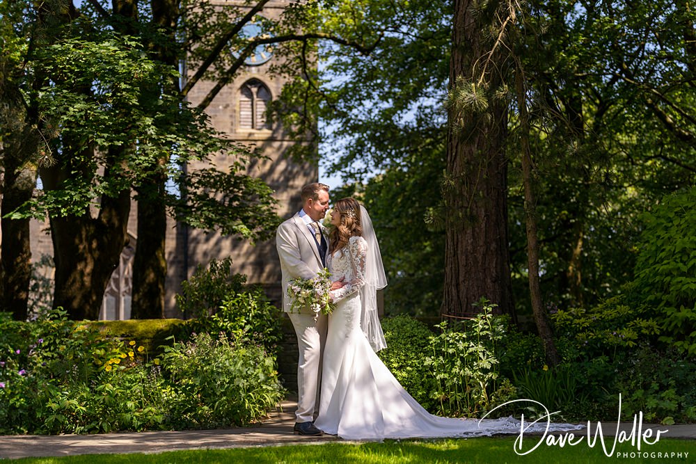 Bride and groom outdoors by church, sunny wedding day.