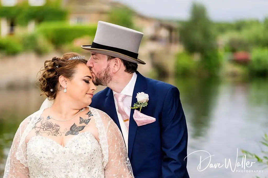 Wedding couple sharing kiss by the river.