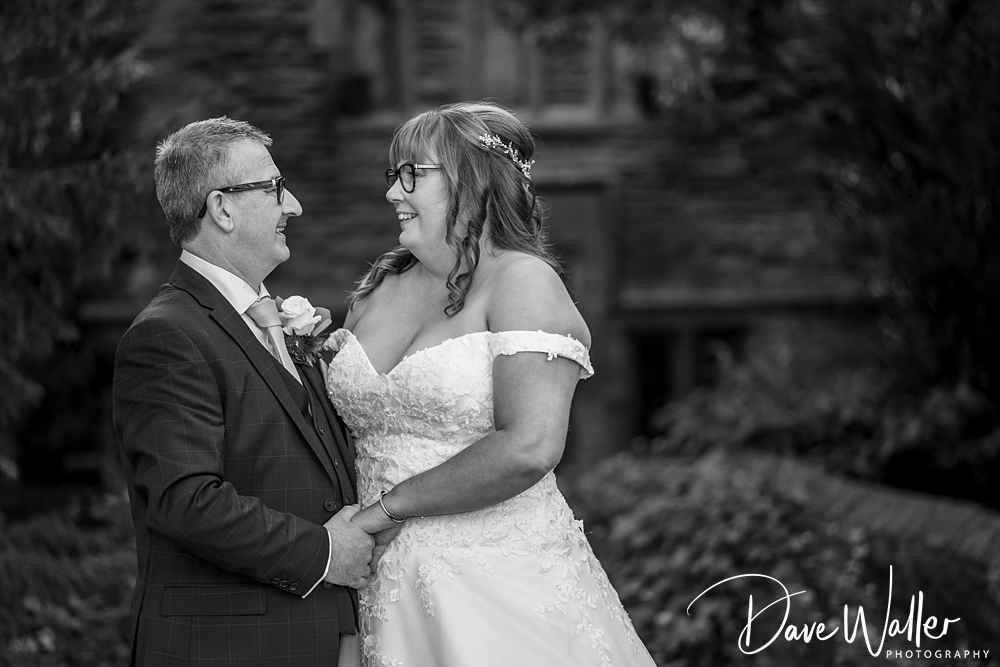 A black and white photo from JOANNE & BRIAN's Wedding shows the bride and groom smiling at each other, holding hands. The bride wears a detailed wedding gown and the groom is in