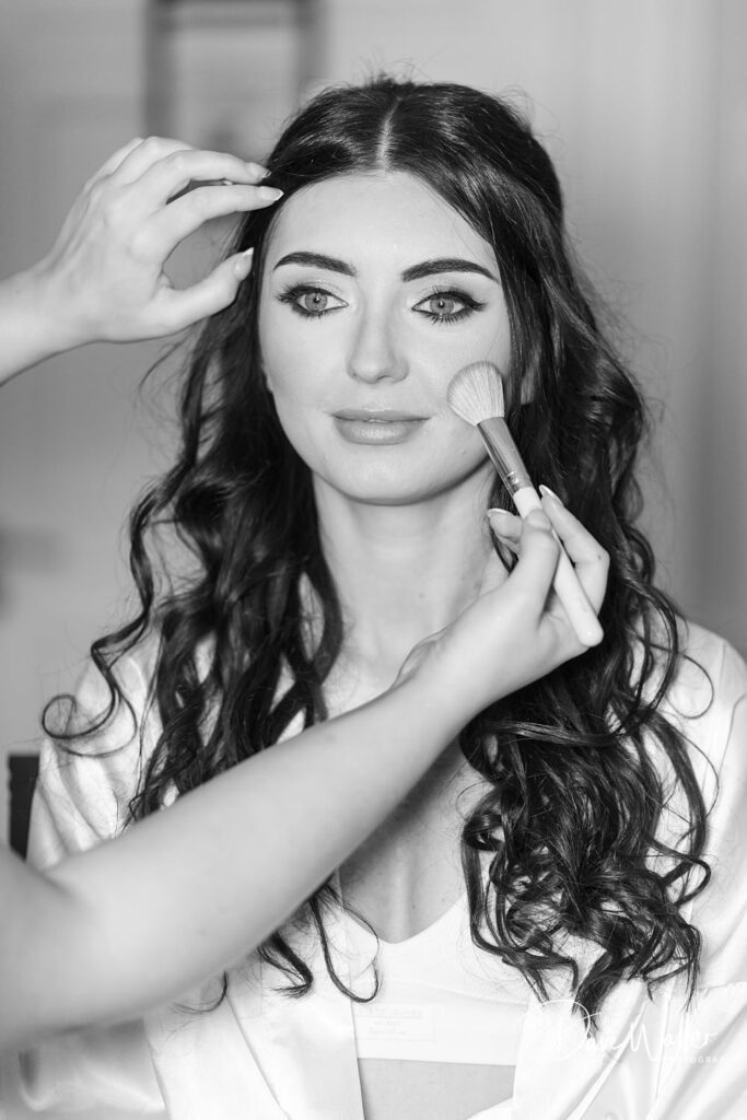 Woman having makeup applied with brush.