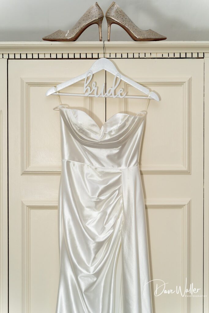 Elegant bridal gown with sparkling shoes displayed.