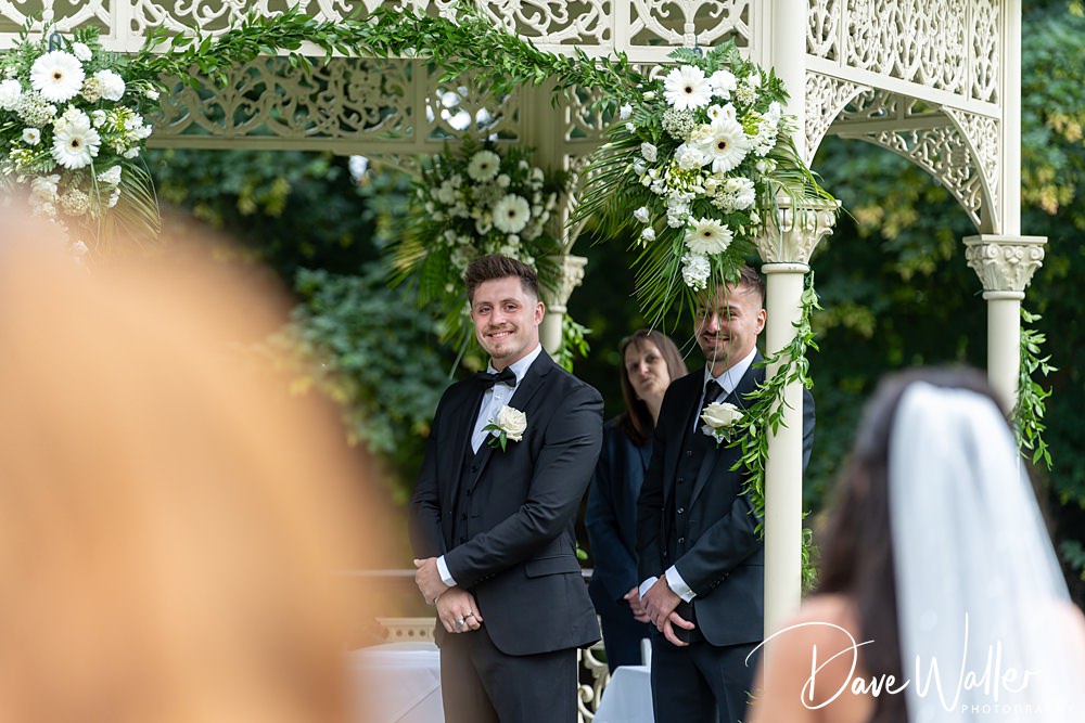 Groom awaits under floral wedding gazebo