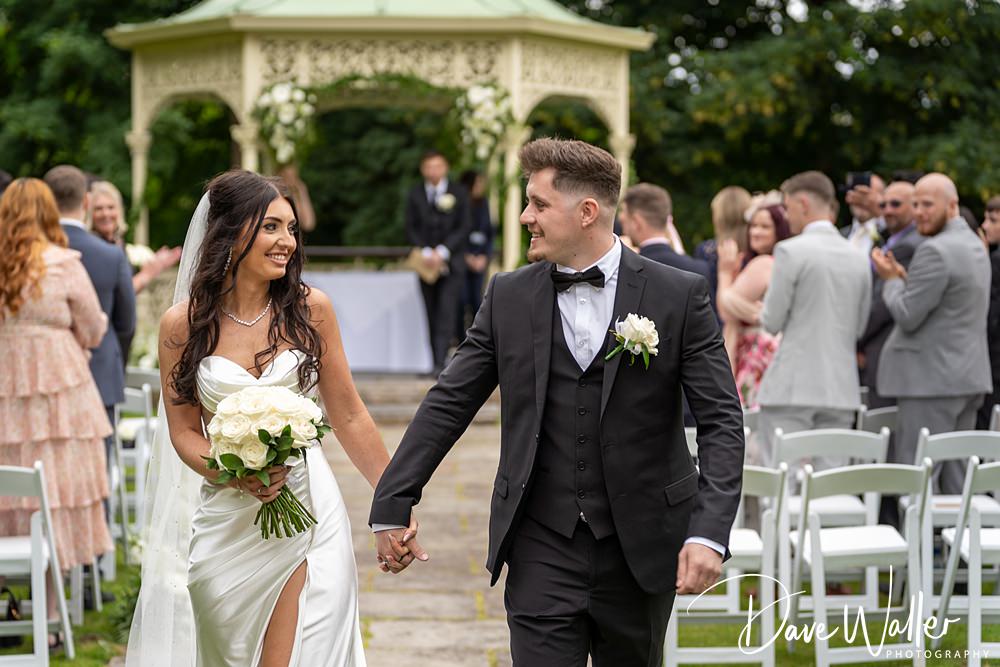 Bride and groom walking down the aisle, smiling.