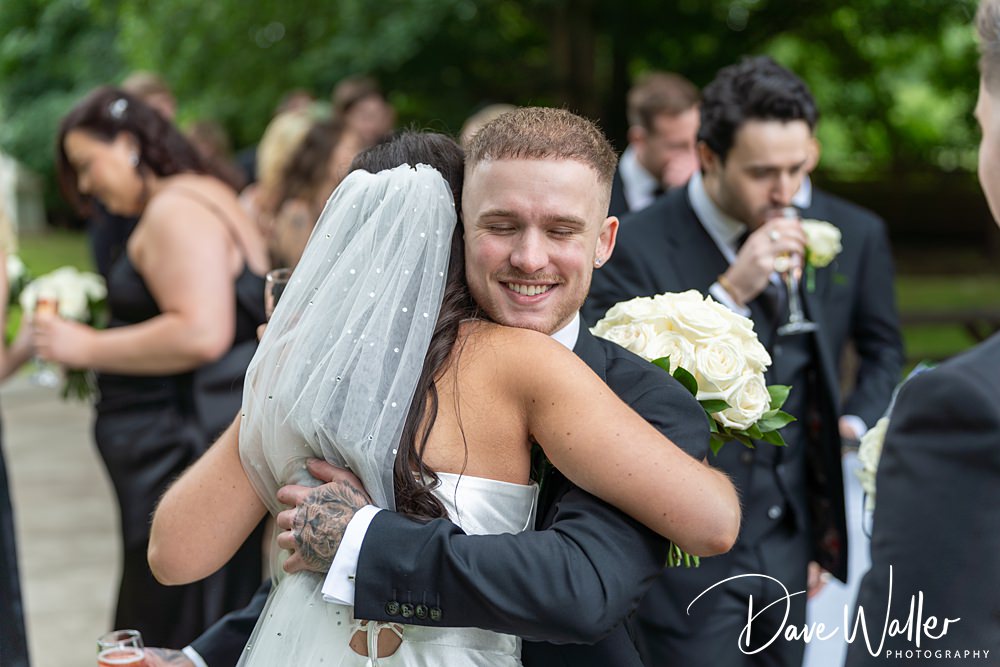 Bride hugs guest with flowers at wedding