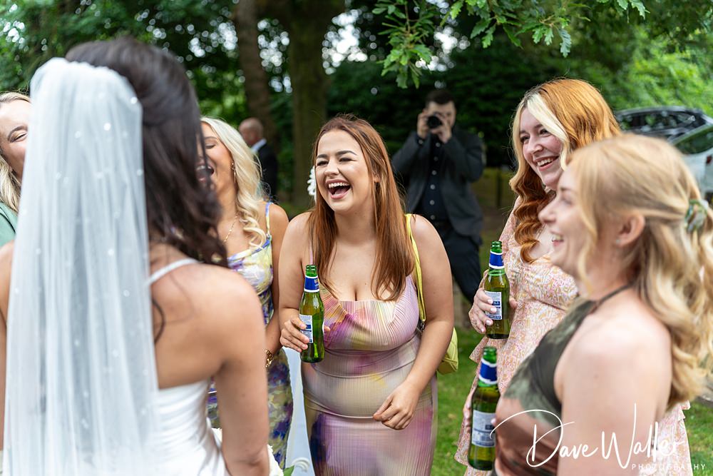 Women laughing and celebrating at outdoor wedding.