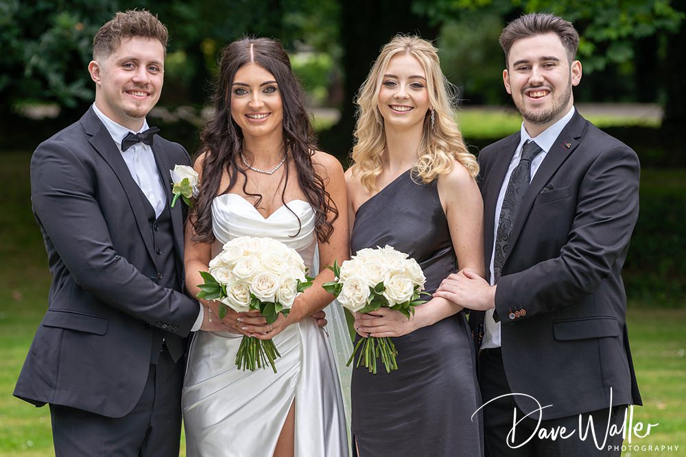 Four people posing with flowers at a wedding