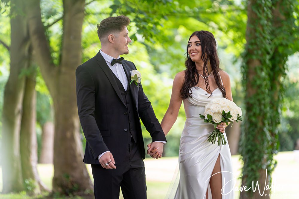 Bride and groom walking outdoors, holding hands.