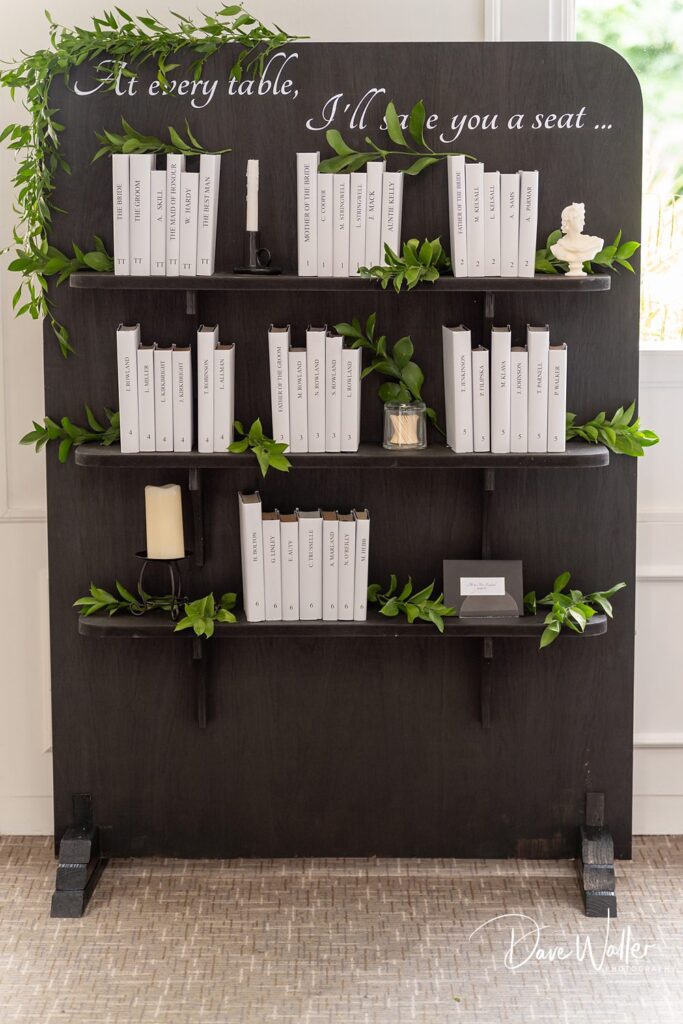Wedding seating chart with books and greenery.