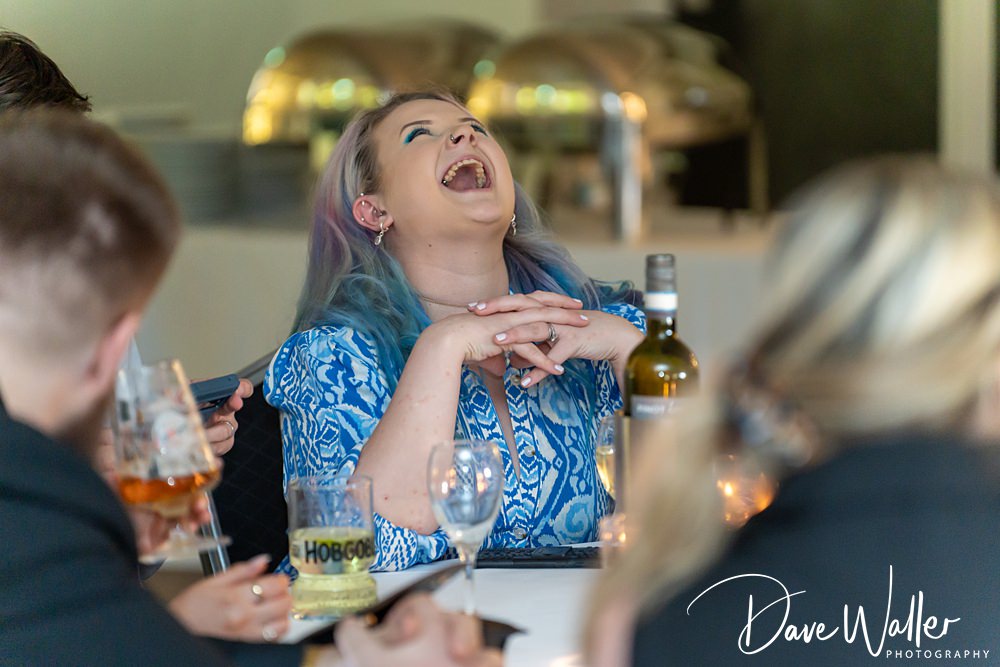 Woman laughing joyfully at a dinner table.
