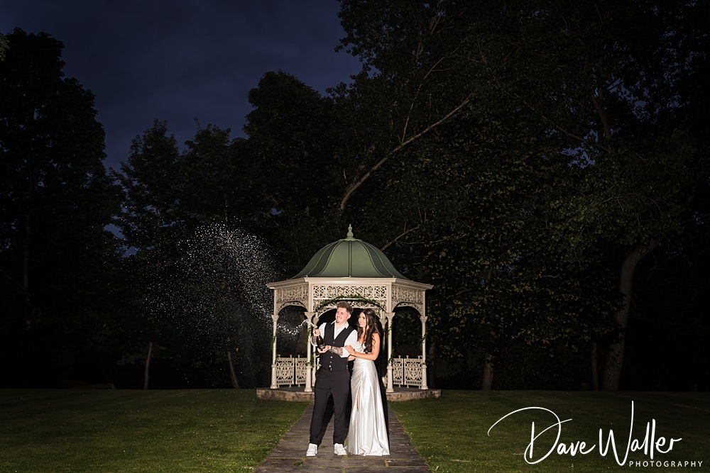 Couple celebrating with champagne in garden gazebo